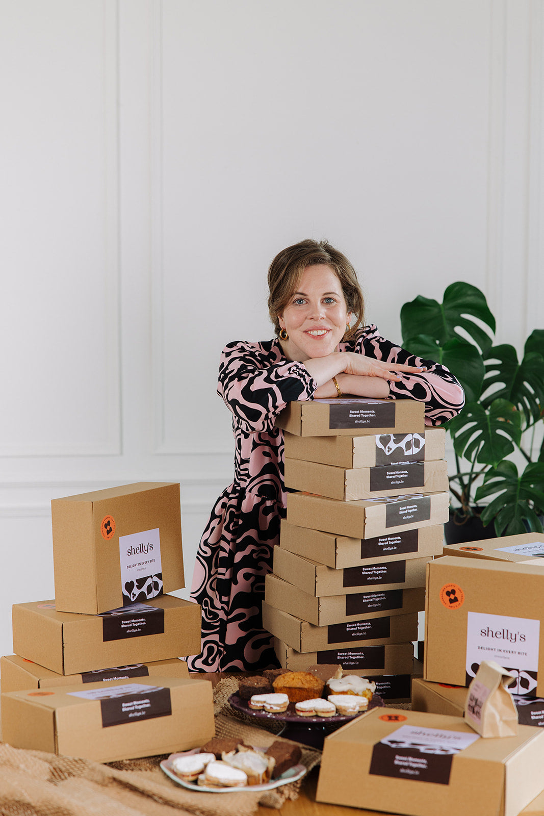 Shelly smiling, leaning on a stack of Shelly's treat boxes