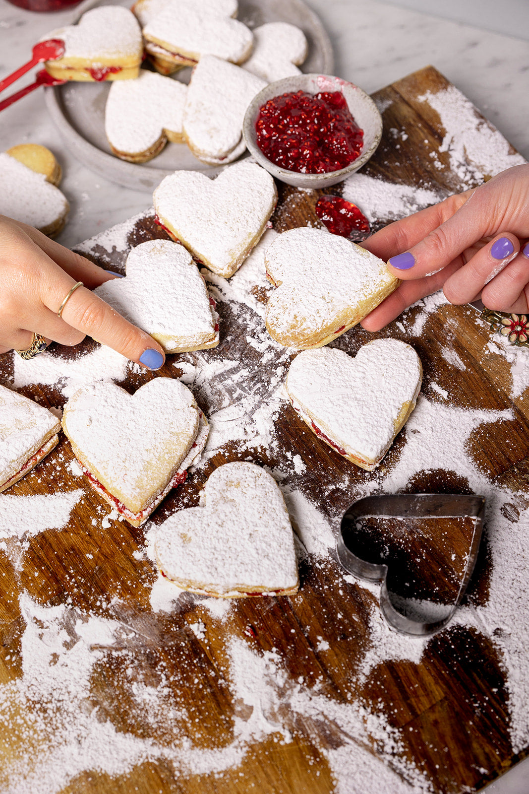 Rows of vanilla shortbread hearts with raspberry jam on pink